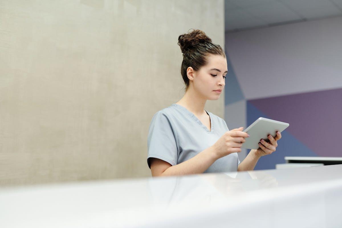 Nurse reviewing staffing information on a tablet at a care facility front desk